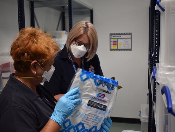 Two forensics officers examine a bag.